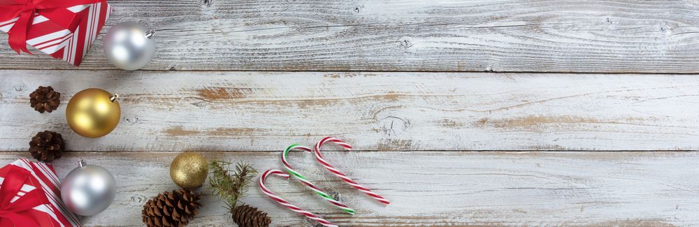 Traditional silver and gold Christmas balls with presents, candy canes and pine cones on wood