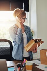 Happy woman on phone while looking at orders