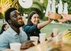 Cheerful woman taking takeaway food near Black man