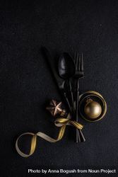 Dark cutlery on dark background tied with festive gold ribbon and ornaments 5Qqoe5