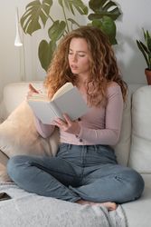 Young woman reading book on sofa
