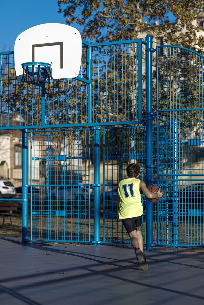 Teenager playing basketball on an outdoors court