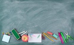 Back to school theme with erased green chalkboard and student supplies