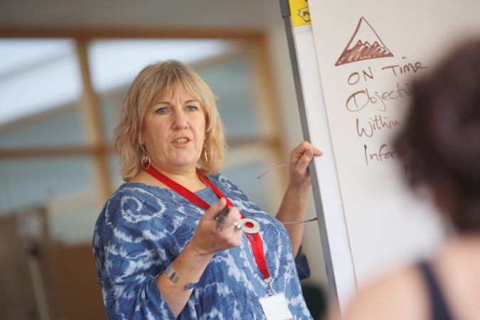 Older woman giving a presentation with a white board