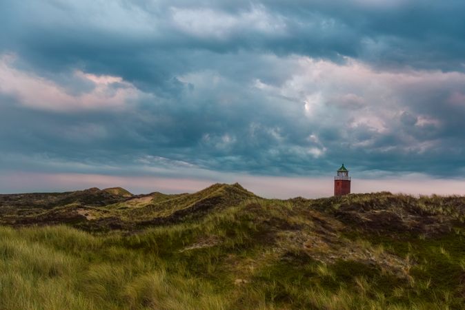 Sunset scenery with lush grass and lighthouse after rain on Sylt island, Germany