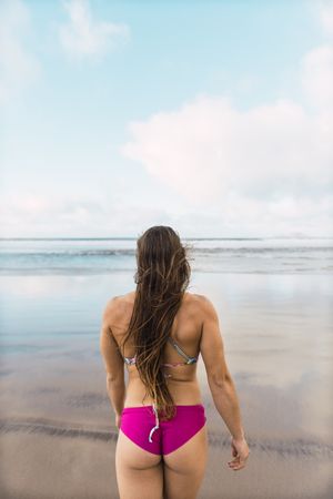 Woman in swimwear running near sea