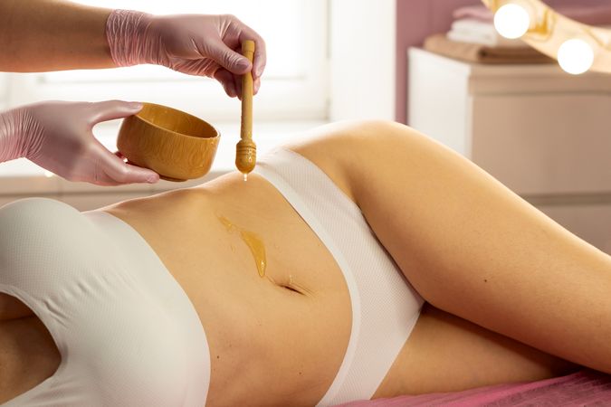 Honey applied to client’s abdomen during cosmetic spa session.