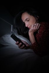 Woman surfing smartphone in darkness