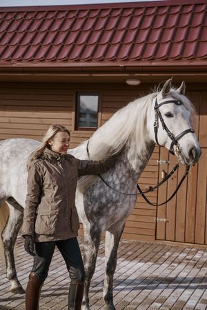 Warm dressed woman with gray horse outside
