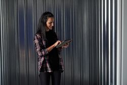 Positive woman browsing tablet near metal storage