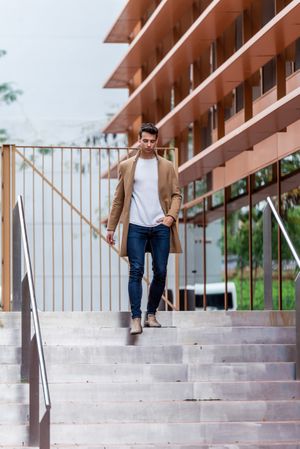 Man in jeans and autumn coat walking down outdoor staircase