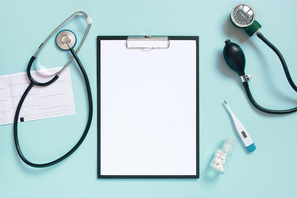 Top view of blue desk with doctor’s equipment and notepad