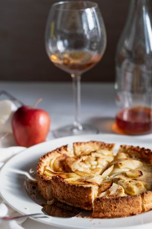 Homemade apple tart on table with red apple and wine glass