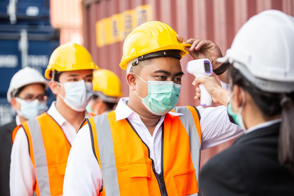 Woman taking temperature of staff on a construction site