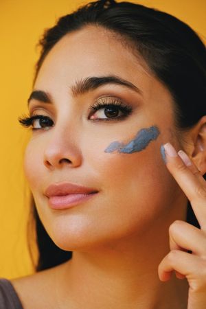 Close up of Latina woman applying clay mask with hand