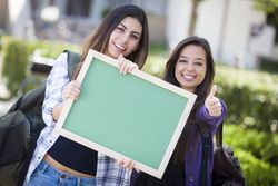 Female Students with Thumbs Up Holding Blank Chalkboard