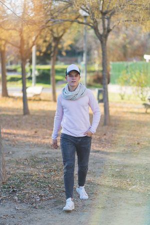 Portrait of a teenage male wearing a cap and walking through park