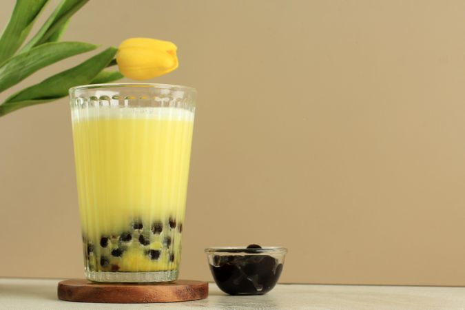 Yellow boba drink staged next to flower