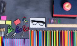 Back to school supplies placed on erased chalkboard, copy space