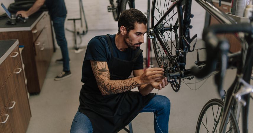 Man with tattoos working on a bicycle in a repair shop