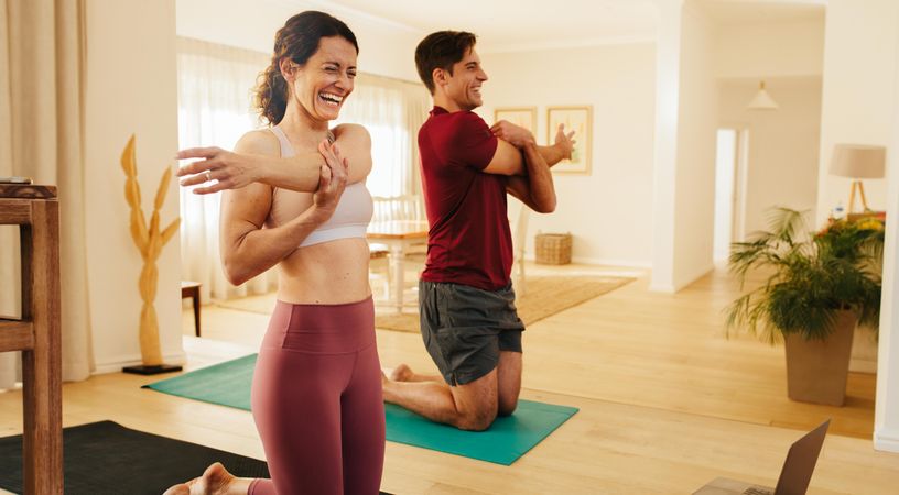 Couple smiling and exercising at home together
