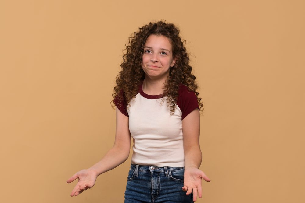 Young girl with shrugging gesture, expressing confusion