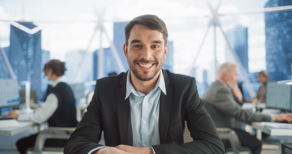 Happy Businessman Looking at Camera And Smiling, Enjoying Day At Work.