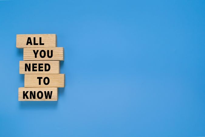all you need to know words text symbol on wooden blocks. isolated on blue background