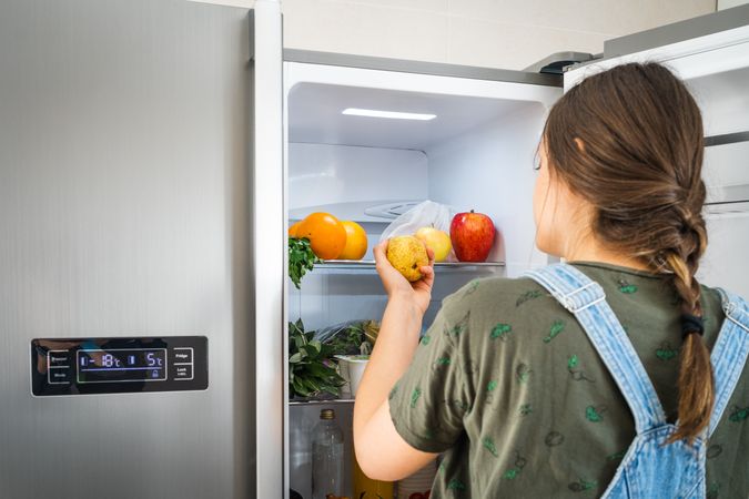 Crop woman taking fruit from fridge