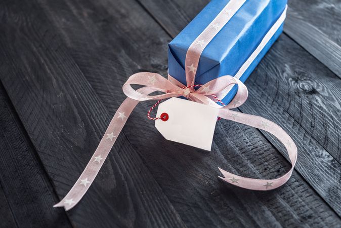 Present wrapped in blue paper on wooden background