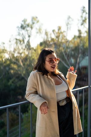 Three quarter shot of stylish young woman waving at camera