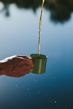 Close up shot of a hand holding a mug with tea pouring in it