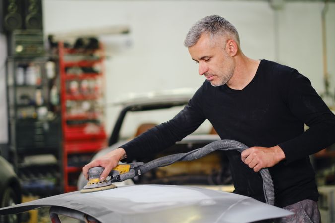 Mechanic grinding paint from car detail
