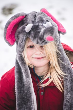 Young girl in red coat wearing rat hat covering the head