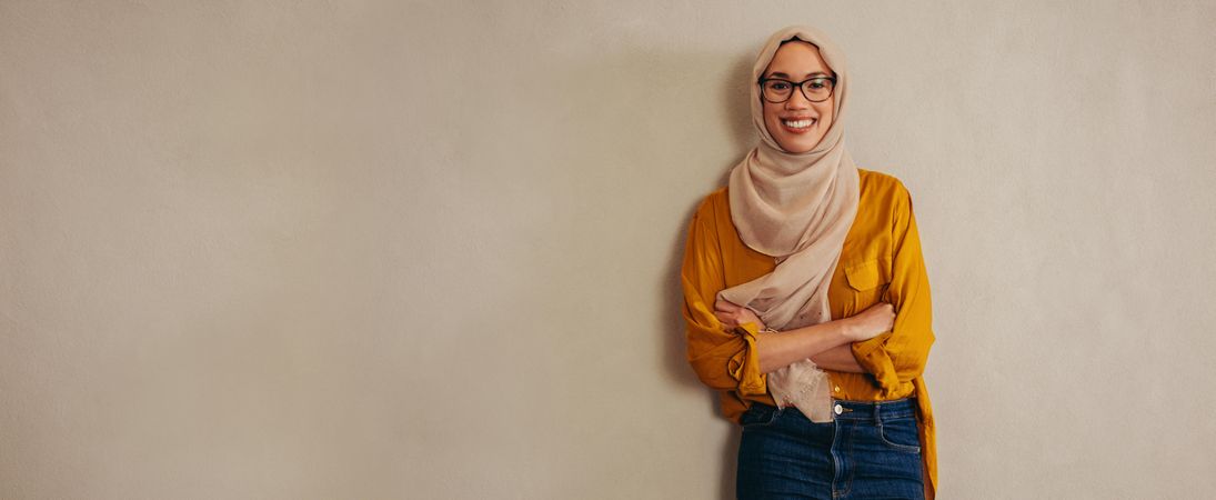 Portrait of a happy muslim woman standing against a wall