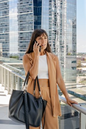 A serious businesswoman is talking on her cell phone outdoors