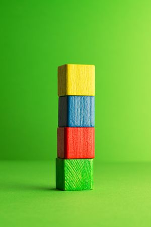 Colorful wooden blocks stacked neatly over green background