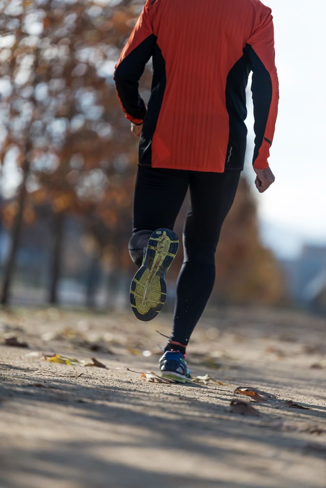 Shoes of male running on cement path in park in the fall