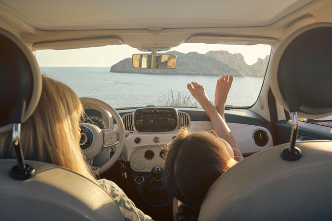 Interior of a car with mother and daughter sitting inside lookin