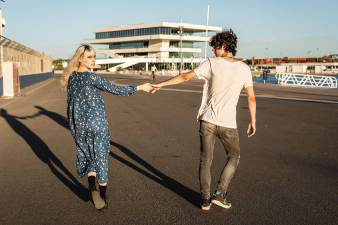 Couple holding hands while walking along road in harbor
