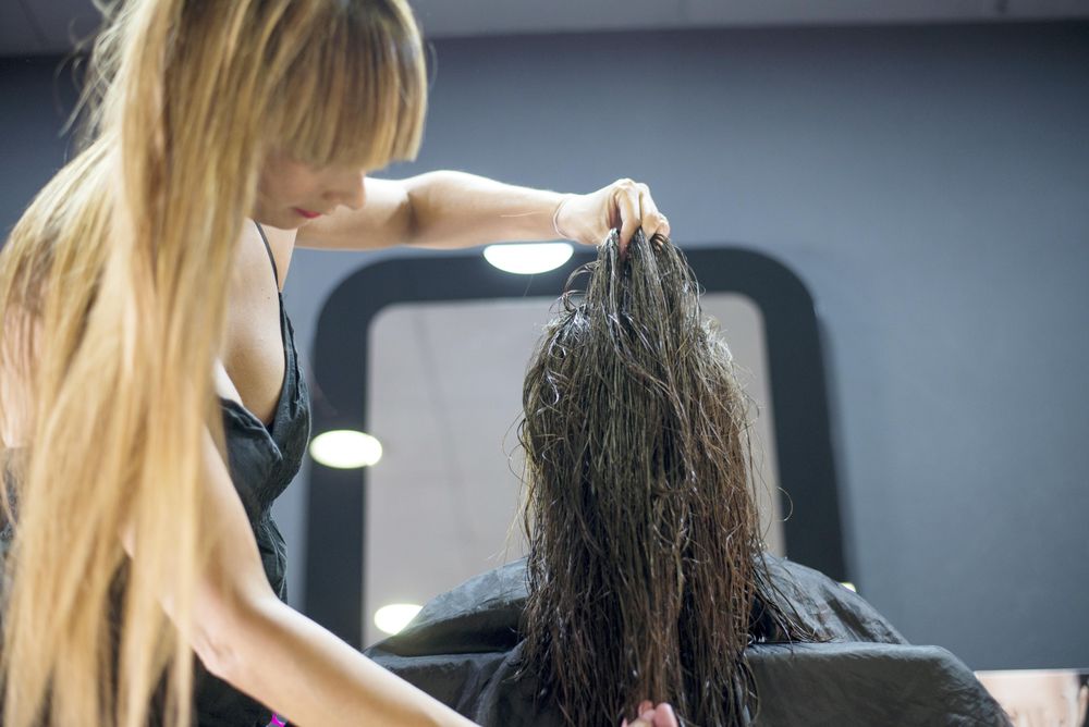 Hair stylist playing with brunette wet hair before cut