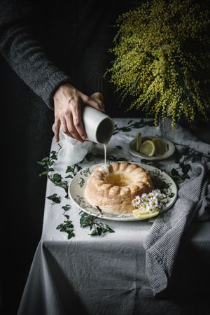 Hand pouring glazing on cake