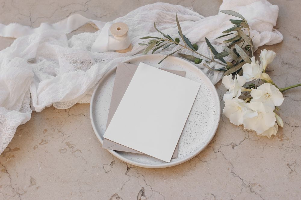 Blank greeting cards on plate with oleander blossom, ribbon and olive tree branches