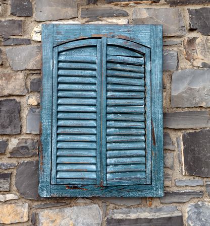 Vintage exterior shutters on aged stone wall