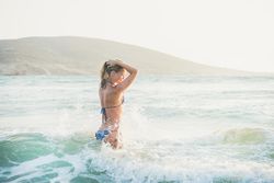 Side shot of woman in bikini in the water at the beach