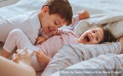 Closeup of happy boy and little girl playing in bed on a relaxed morning 56Oqx4