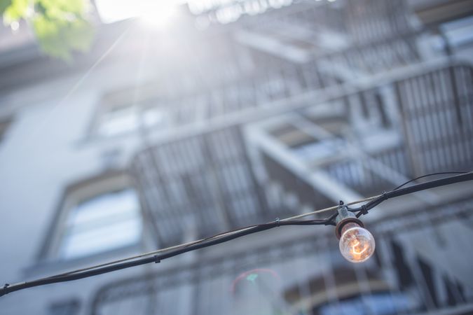 Illuminated lamp on street near building in sunny day