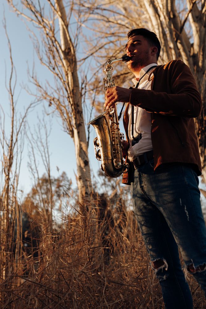 young musician playing the saxophone at sunset
