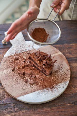 Crop woman preparing chocolate cake with cocoa powder