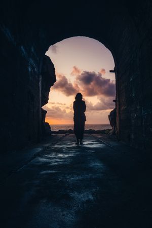 Silhouette of person walking in tunnel